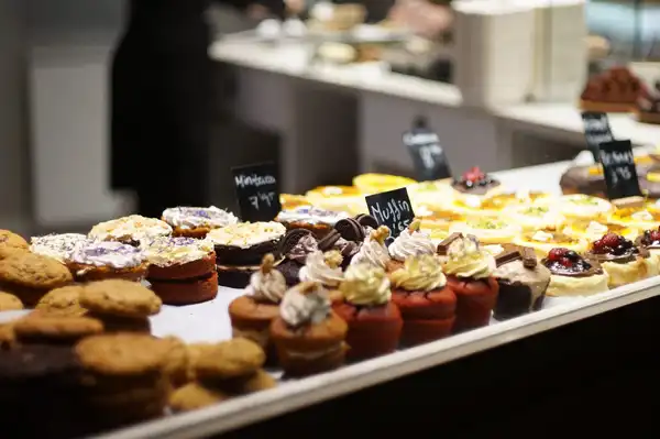 A bakery counter of cupcakes and pastries with handwritten chalk labels
