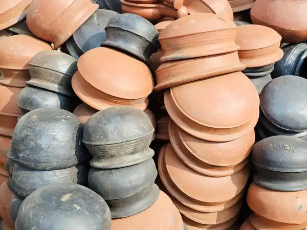 A heap of terracotta and grey clay pots with lids