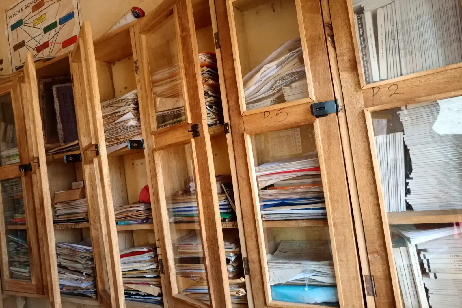 Tall wooden cabinets with glass doors holding magazines and papers