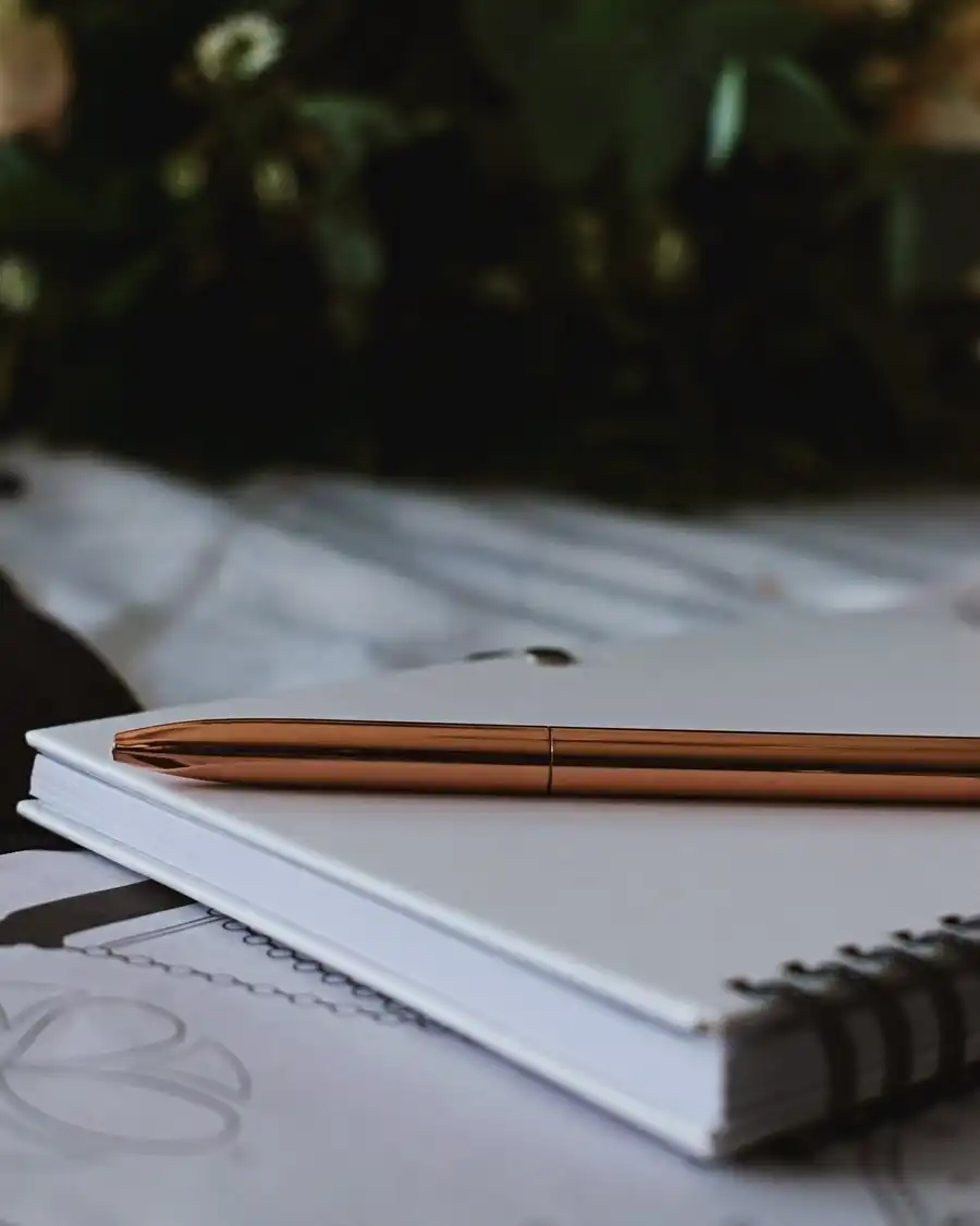 Two copper pencils on a white spiral notebook on a desk