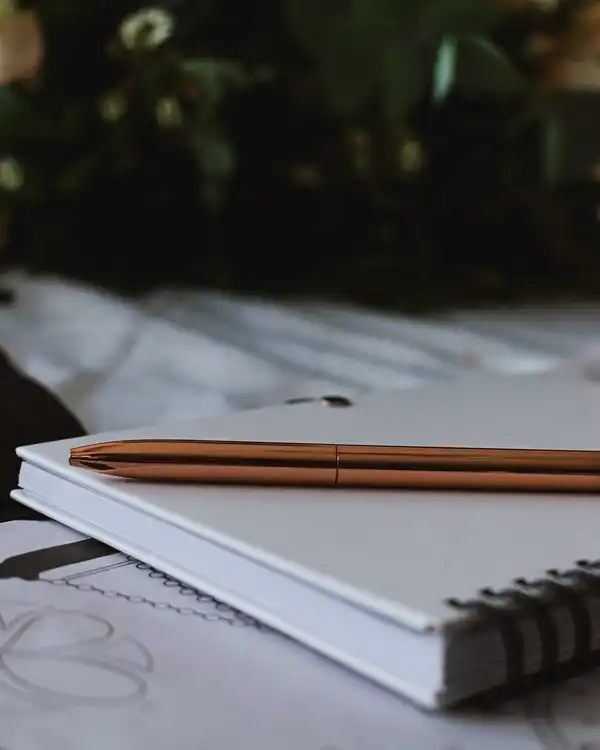 Two copper pencils on a white spiral notebook on a desk